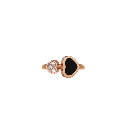 Chopard Ring Happy Hearts aus 18 Karat Roségold. Die beiden zueinander gedrehten und unterschiedlich großen Herzen sind mit unterschiedlichen Materialien ausgefasst. In dem größeren Herz liegt ein schwarzer Onyx, während in dem kleinen Herz ein Brillant zwischen zwei Saphirgläsern tänzelt.